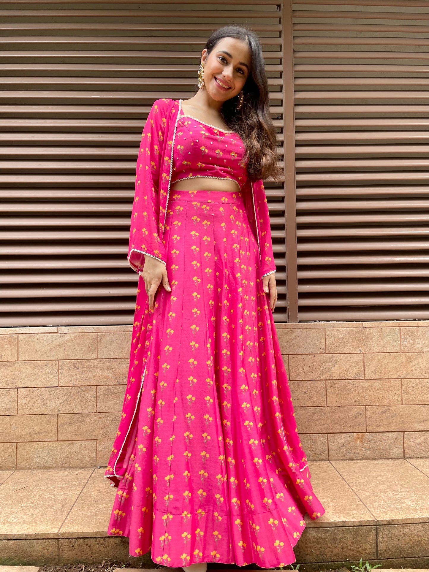 Rani pink floral printed lehenga with a printed blouse highlighted with intricate hand embroidery and cape